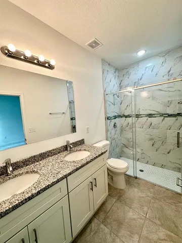 a bathroom with a granite countertop sink toilet and shower