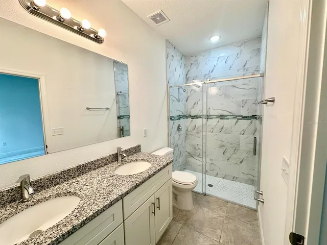 a bathroom with a granite countertop sink a toilet and shower