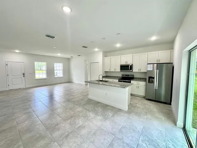 a large kitchen with stainless steel appliances lots of white cabinets