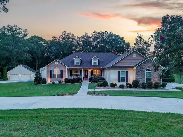 a view of a big house with a big yard plants and large trees