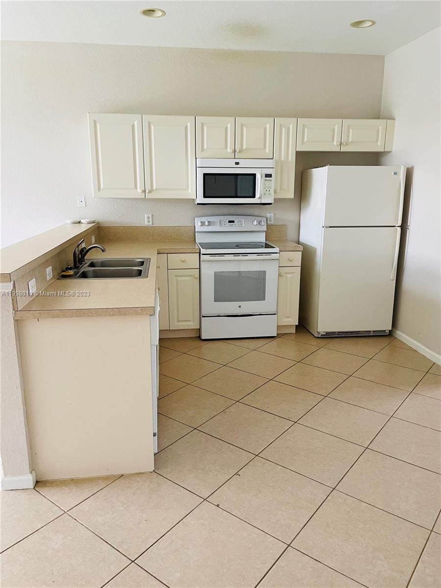 Riviera Beach Riviera Beach, FL 33404 - Photo 5 of 10 a kitchen with a stove a sink and a refrigerator