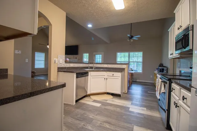 a large kitchen with stainless steel appliances granite countertop a stove and a sink