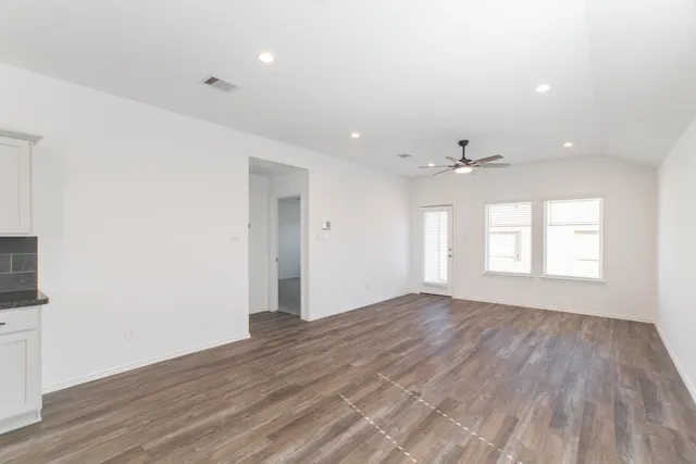 an empty room with wooden floor and windows