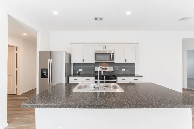 a kitchen with stainless steel appliances granite countertop a sink refrigerator and microwave