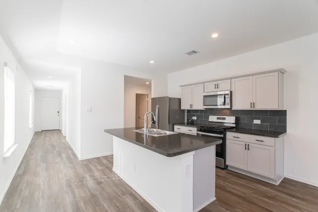a kitchen with stainless steel appliances granite countertop a sink stove and refrigerator