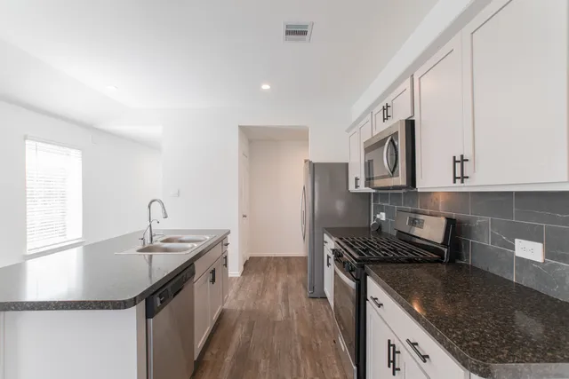 a kitchen with stainless steel appliances granite countertop a sink stove and refrigerator