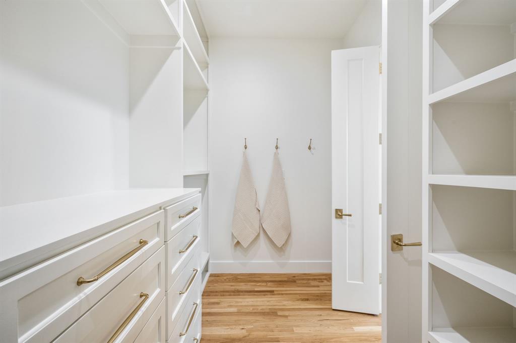 3304 Ferguson Road Grapevine, TX 76092 - Photo 29 of 38 Dedicated closet system featuring custom white cabinetry with gold-tone hardware, integrated shelving, and wood-finish flooring