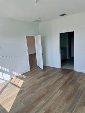 an empty room with wooden floor and entrance