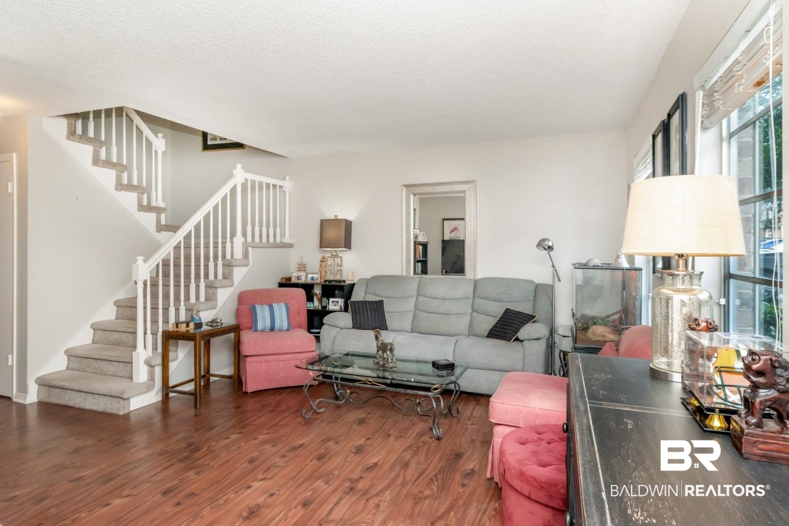118 Du Rhu Drive, Unit H Mobile, AL 36608 - Photo 4 of 19 Open-concept living space with wood-finish flooring, a carpeted staircase with white railings, and large windows providing natural illumination