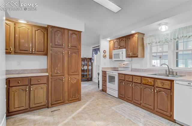 12825 Garrett Road Peyton, CO 80831 - Photo 17 of 47 Kitchen featuring sink, white appliances, and light tile patterned flooring