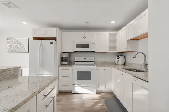 a kitchen with stainless steel appliances granite countertop a stove a sink and a refrigerator with white cabinets