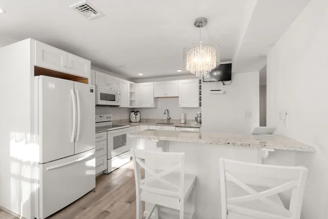 a kitchen with granite countertop a refrigerator a sink and white cabinets