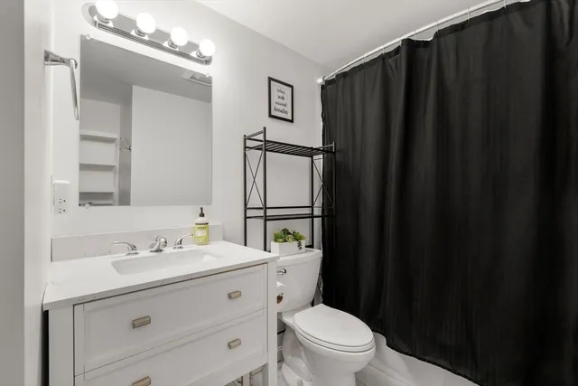 a bathroom with a granite countertop toilet sink and mirror
