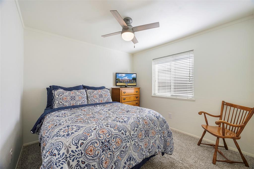 5810 Galaxie Road Garland, TX 75044 - Photo 18 of 33 a bed sitting in a bedroom next to a window and a chandelier