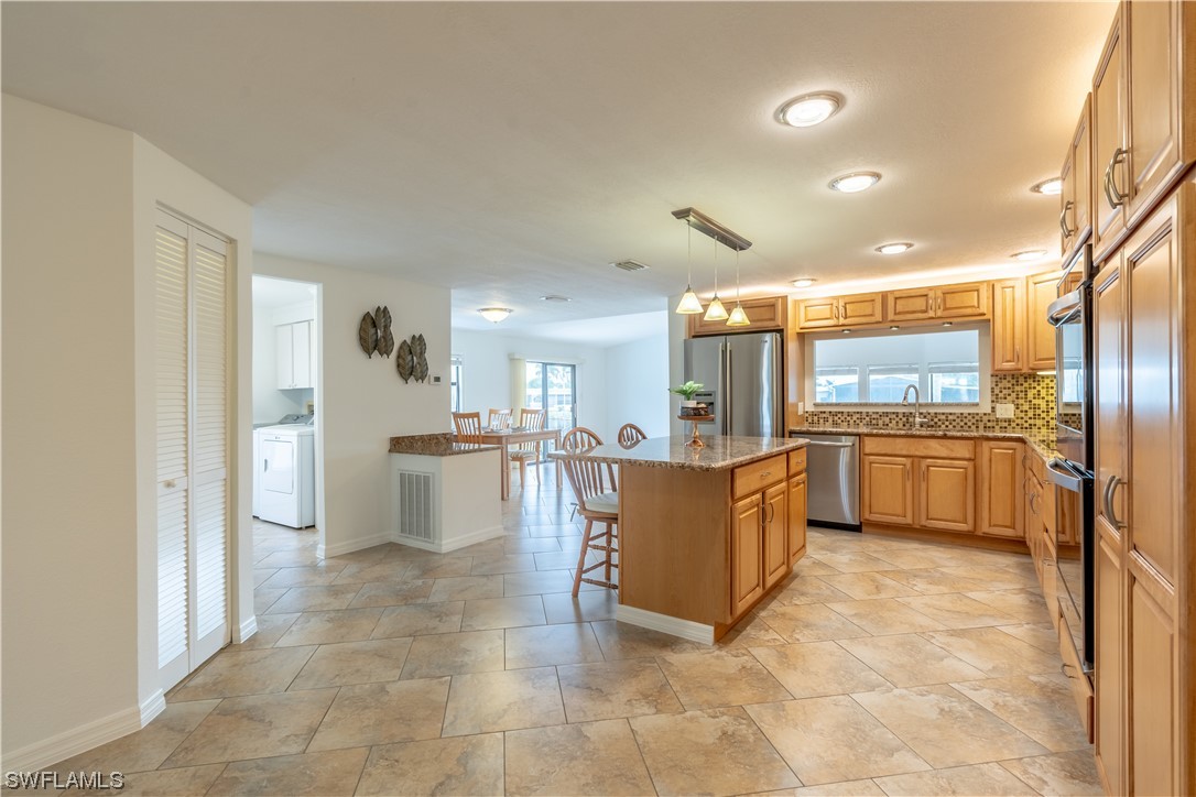 109 Audubon Road Naples, FL 34114 - Photo 4 of 41 a large kitchen with kitchen island a counter top space a stove a refrigerator and white cabinets