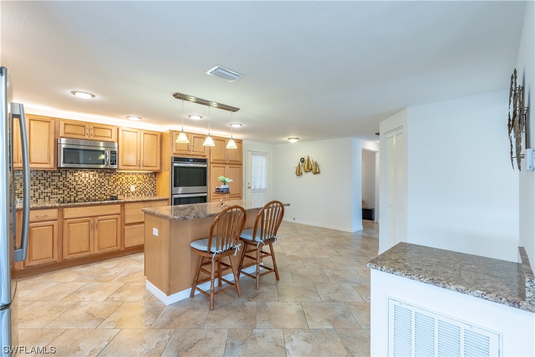 109 Audubon Road Naples, FL 34114 - Photo 7 of 41 a kitchen with granite countertop sink table and chairs