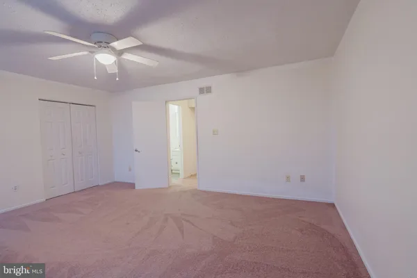 an empty room with a chandelier fan and windows