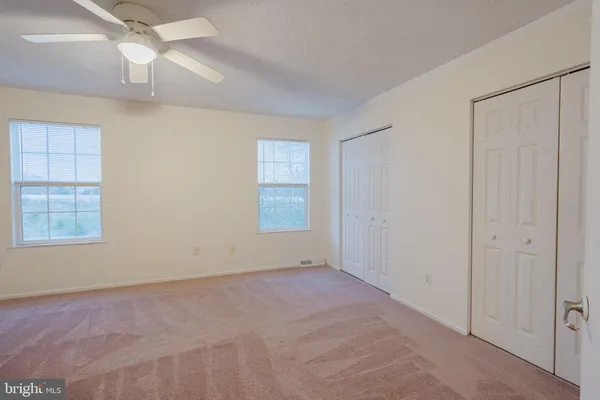 an empty room with a window and ceiling fan