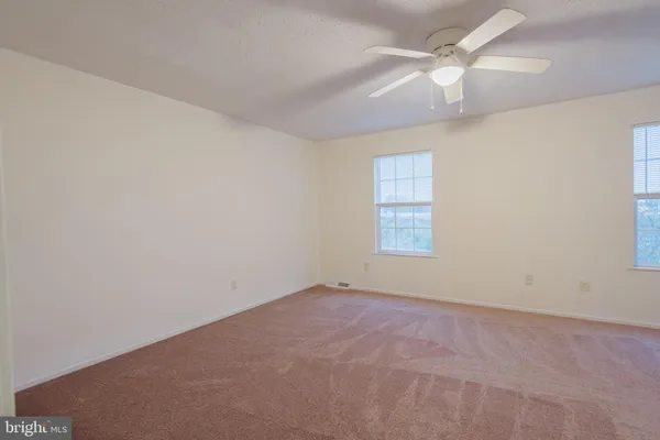 an empty room with a window and ceiling fan