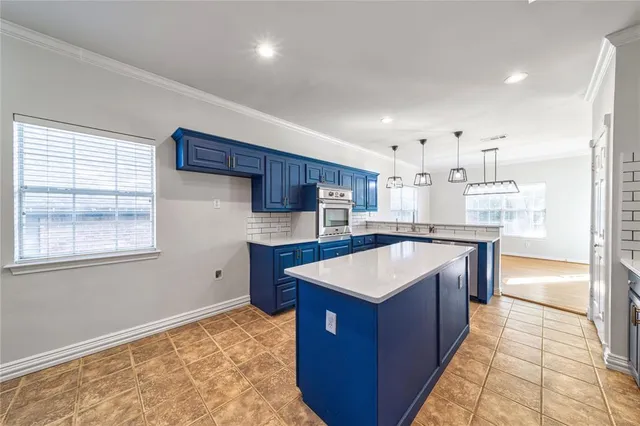 a large kitchen with kitchen island a large counter top and stainless steel appliances