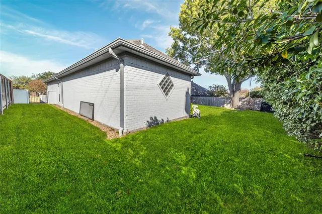 a backyard of a house with plants and large tree