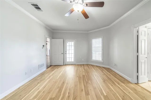 a view of empty room with wooden floor and fan