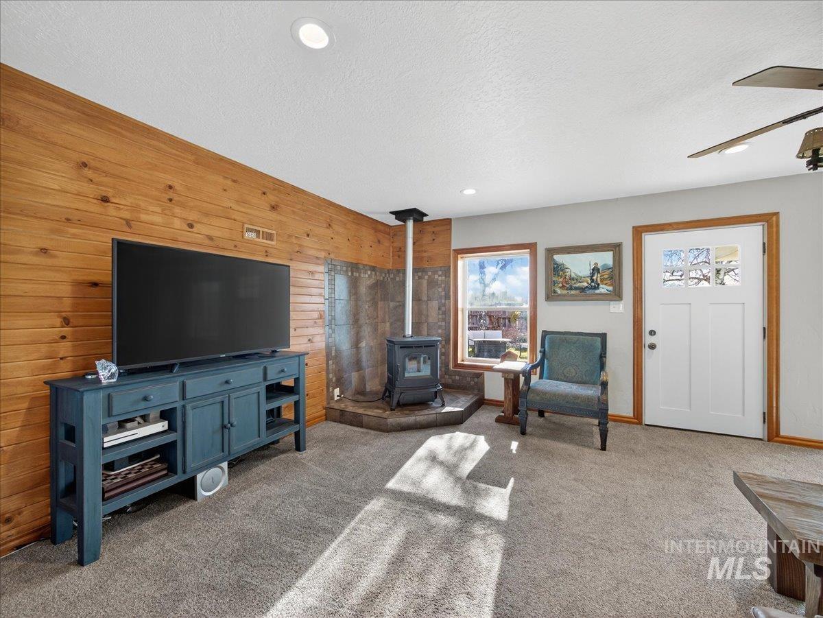 2588 West Sales Yard Road Emmett, ID 83617 - Photo 27 of 49 Living area with wood walls, a wood stove, light carpet, a textured ceiling, and recessed lighting