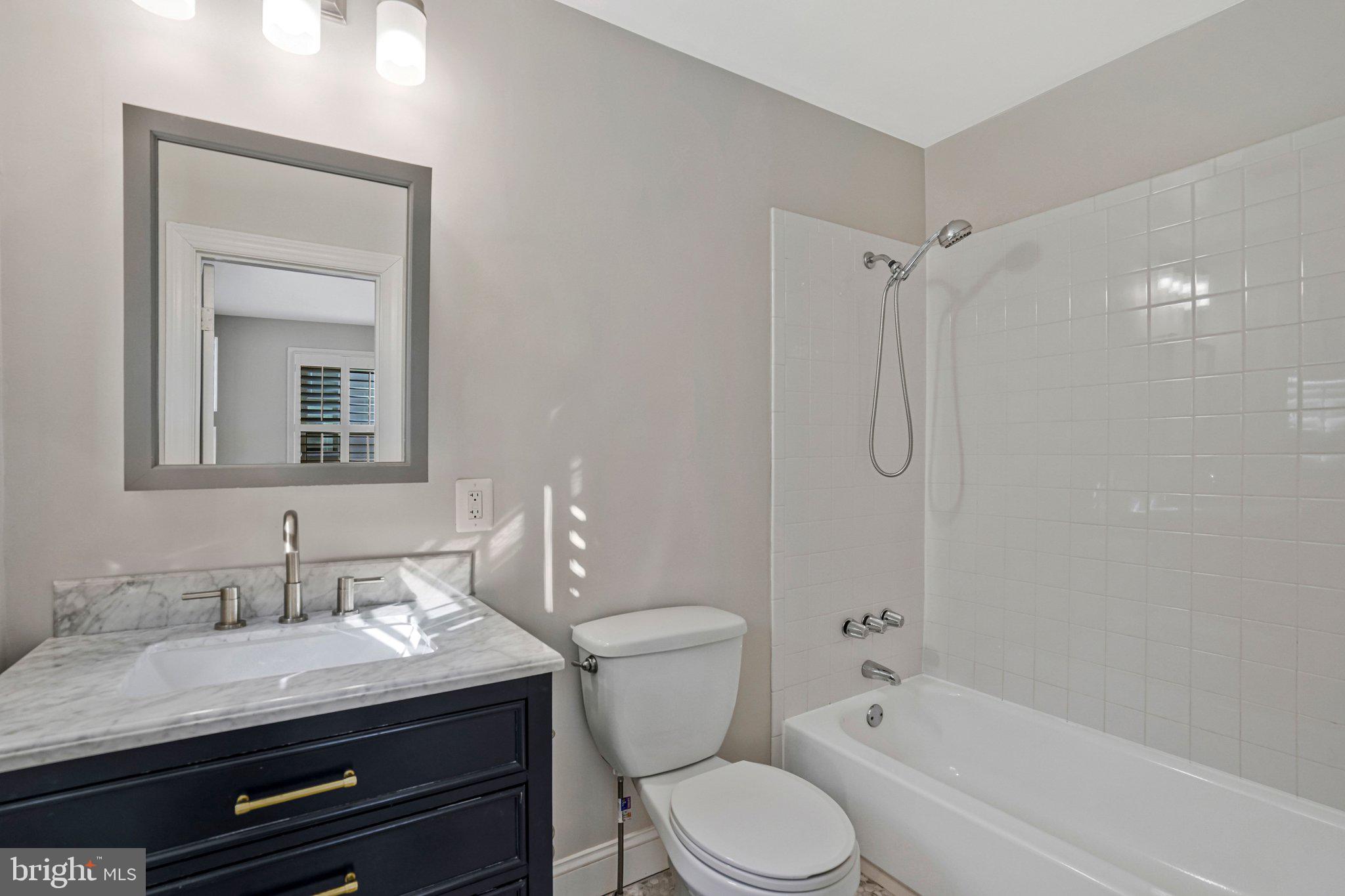 4140 21st Road North Arlington, VA 22207 - Photo 19 of 30 a bathroom with a granite countertop sink toilet a mirror and shower
