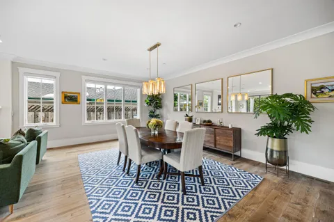 a dining room with furniture wooden floor a rug a potted plant and a chandelier