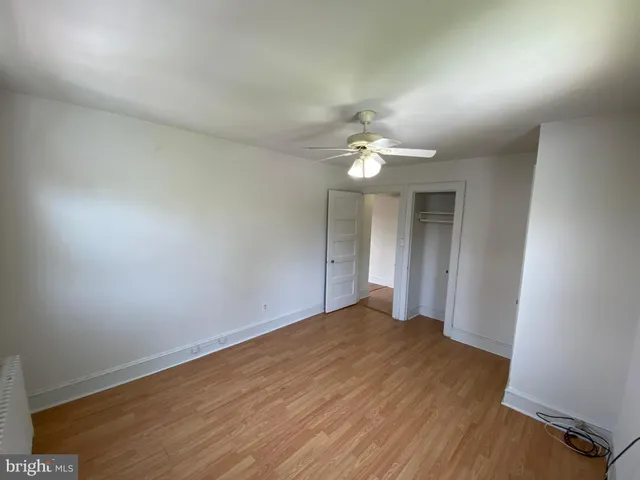 an empty room with wooden floor and chandelier fan