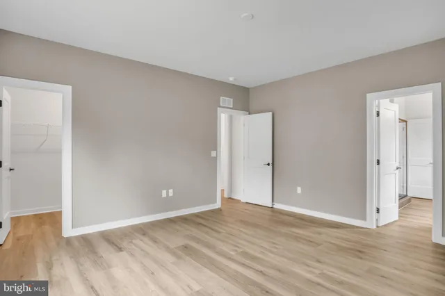 a view of an empty room with wooden floor and closet
