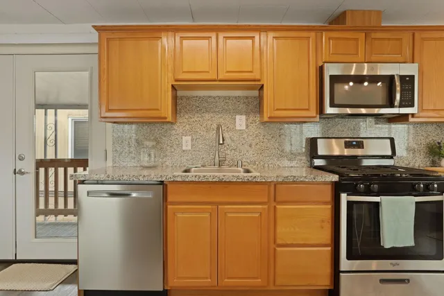a kitchen with stainless steel appliances granite countertop a stove a sink and a microwave