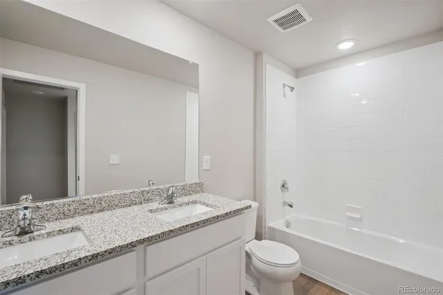 a bathroom with a granite countertop sink a toilet and bathtub