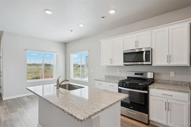 a kitchen with granite countertop stainless steel appliances a stove sink and microwave
