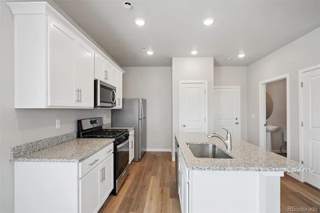 a kitchen with a sink stove top oven and white cabinets