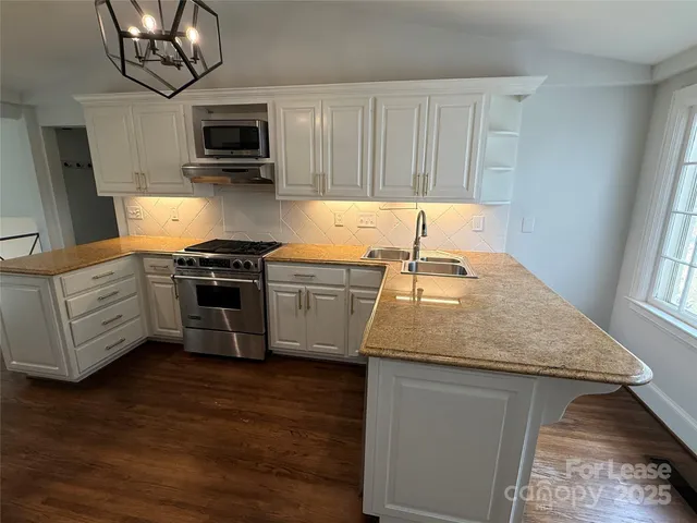 a kitchen with stainless steel appliances granite countertop a sink dishwasher stove and microwave with wooden floor