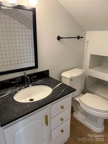 a bathroom with a granite countertop sink toilet and mirror