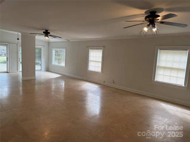 an empty room with windows and ceiling fan