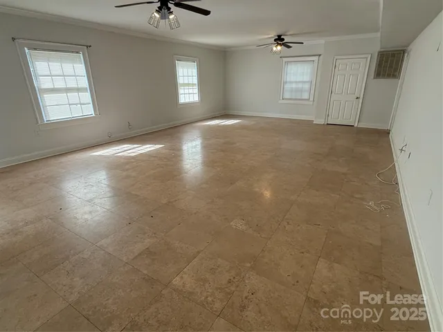 en empty room with windows and chandelier fan