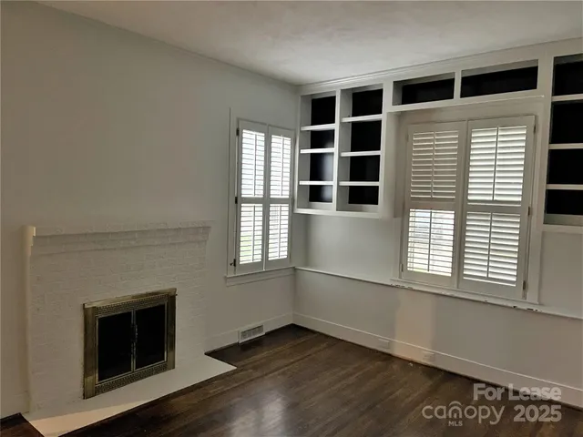 a view of an empty room with a window and fireplace