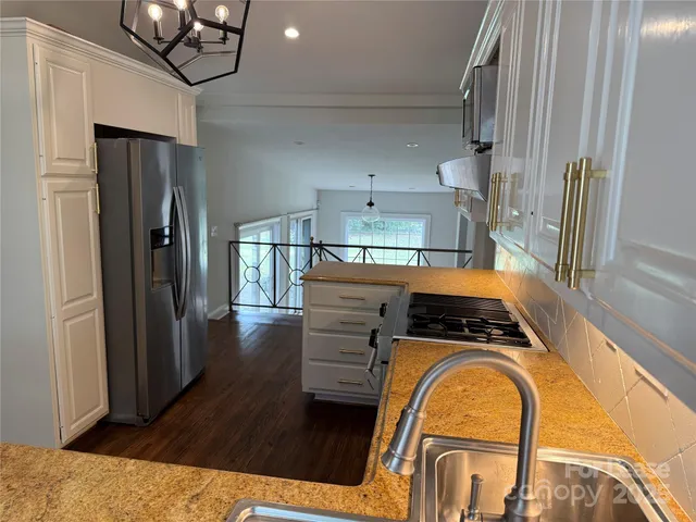 a kitchen with stainless steel appliances granite countertop a refrigerator a stove and a sink