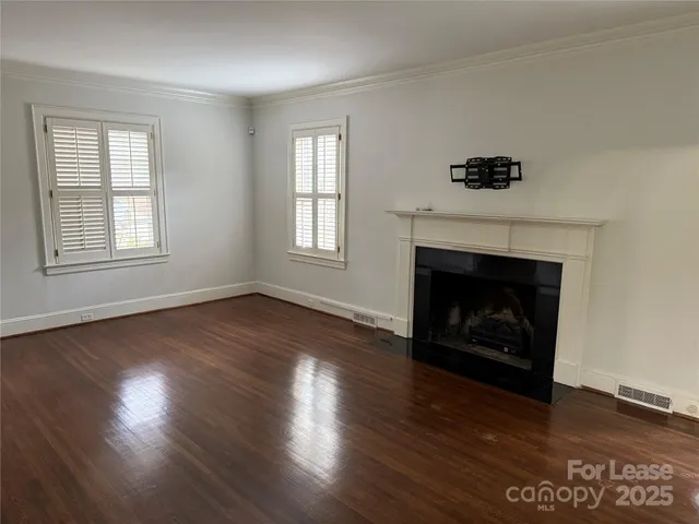 an empty room with wooden floor a fireplace and windows