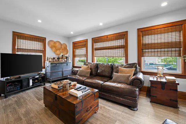 a living room with furniture a flat screen tv and a floor to ceiling window