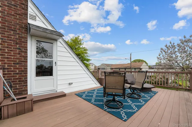 a view of a roof deck with table and chairs a barbeque with wooden floor and fence