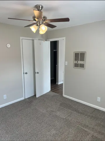 an empty room with a chandelier fan and windows