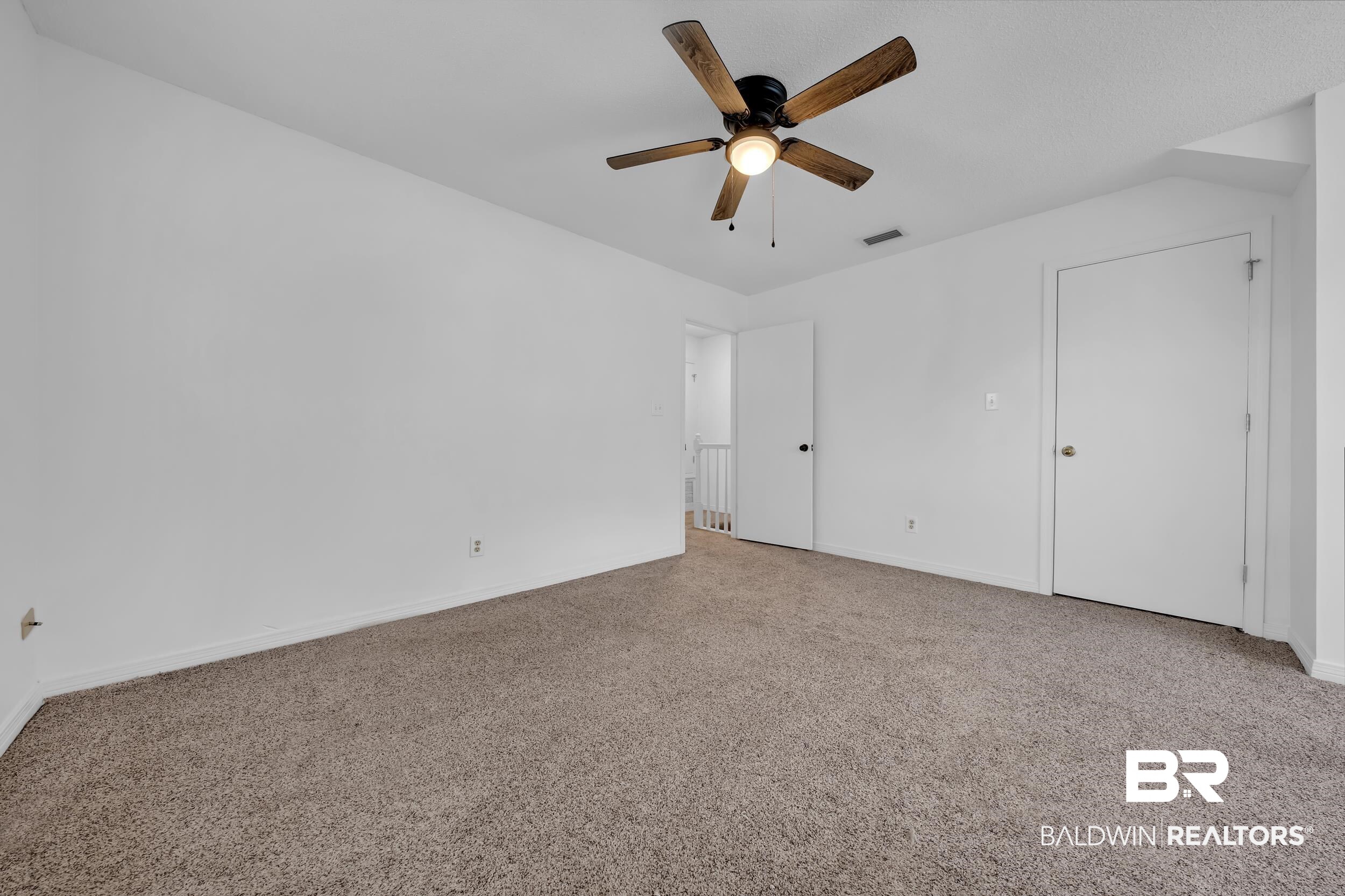 17488 Pandion Ridge, Unit A1 Fairhope, AL 36532 - Photo 14 of 18 Spacious room featuring neutral carpeting, a ceiling fan with wood-finish blades, and white painted walls