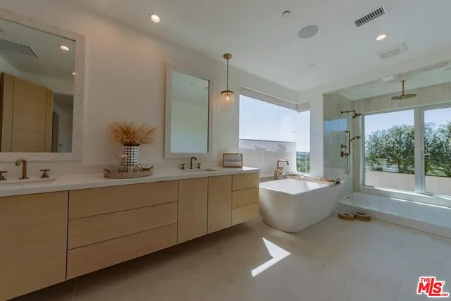 a bathroom with a double vanity sink mirror and bathtub