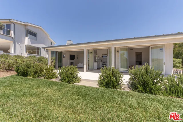 a view of a house with brick walls plants and large tree