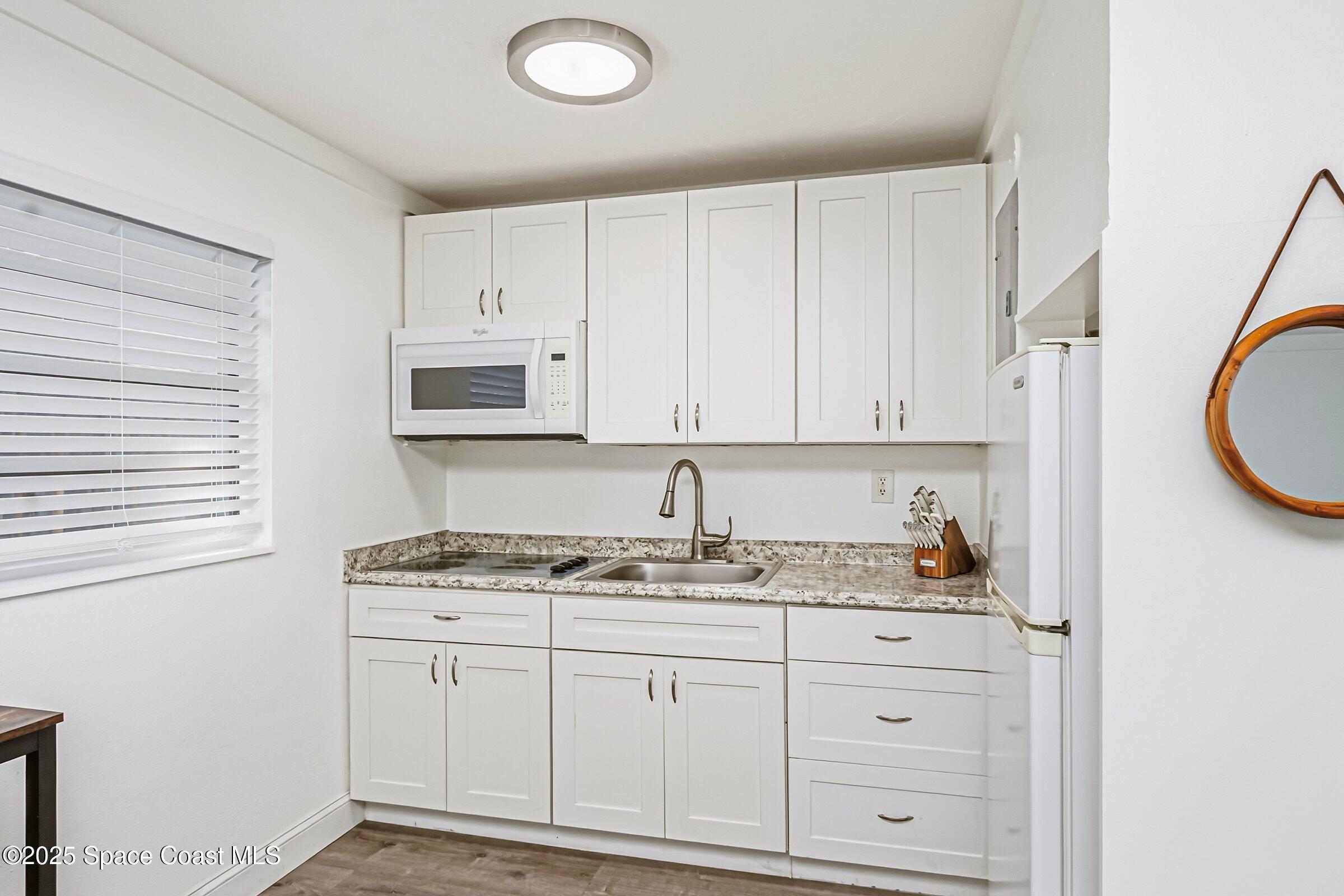 300 South Orlando Avenue, Unit 4 5 6 Cocoa Beach, FL 32931 - Photo 27 of 56 a kitchen with cabinets appliances a sink and a window