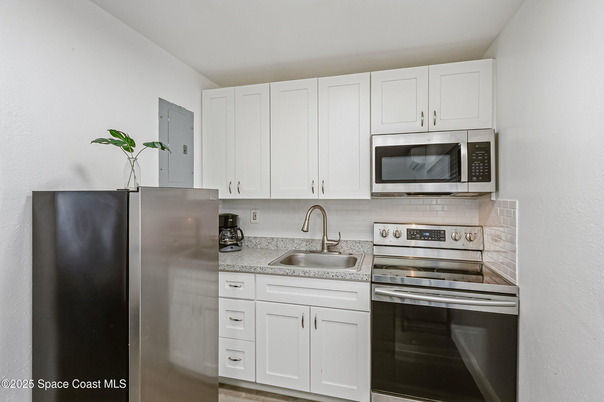 300 South Orlando Avenue, Unit 4 5 6 Cocoa Beach, FL 32931 - Photo 38 of 56 a kitchen with appliances a microwave and cabinets